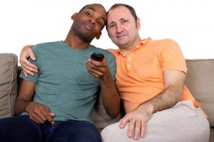 Black man and white man embrace on couch