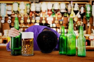 A man lies on bar surrounded by beer bottles