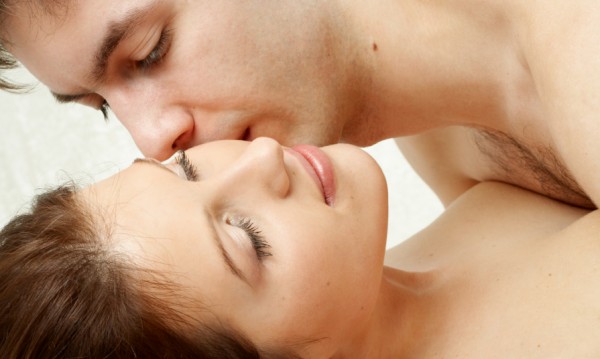 Man on top of woman kissing her neck