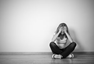 girl sits in a depression on the floor near the wall