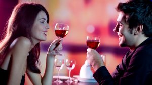 Young happy amorous couple celebrating with red wine at restaura