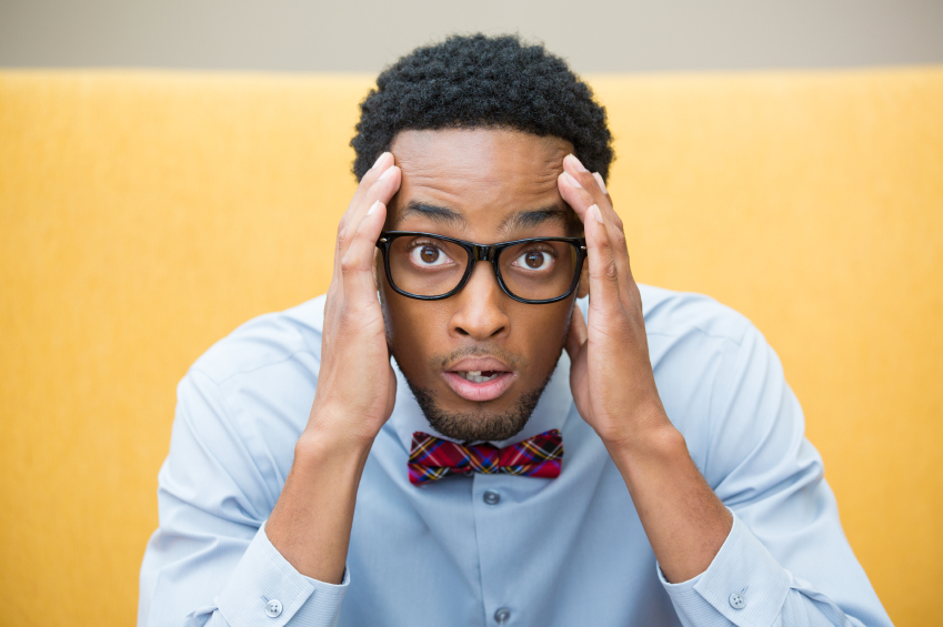 Black man with glasses and a suit looking stressed