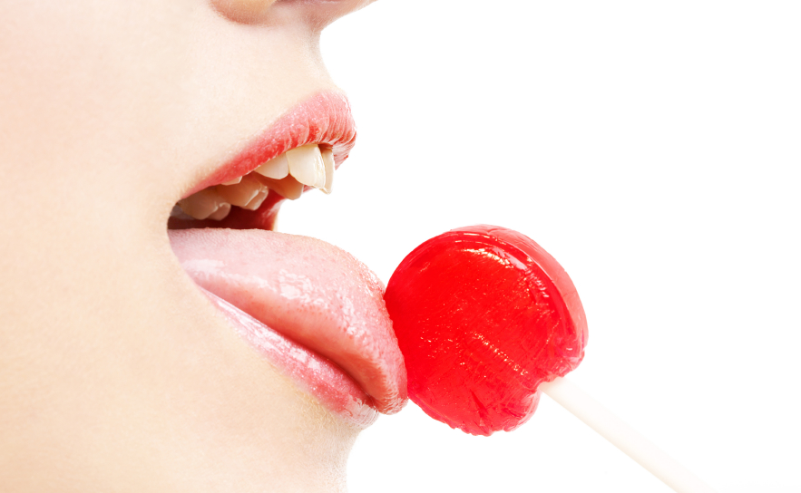 A sexy woman licking a red lollipop