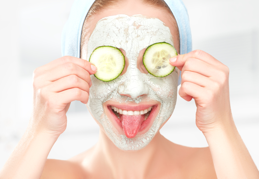Funny young girl with a mask for skin face and cucumbers on eyes