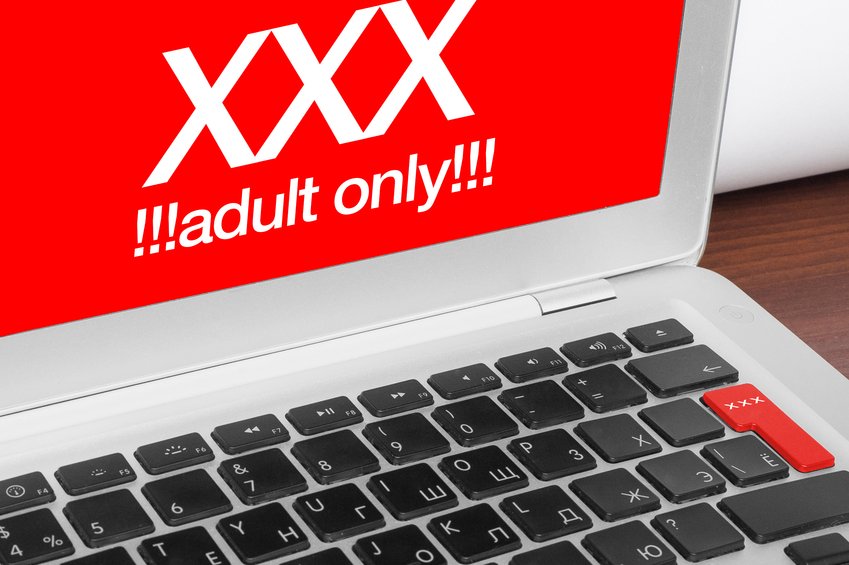 Online porn concept. XXX adults only message on silver laptop and red xxx button on keyboard.