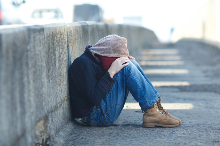 Sad boy sitting in street