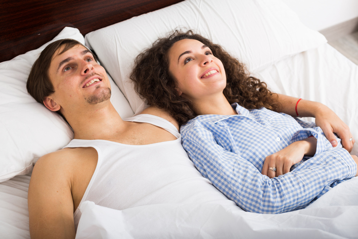 Couple leaning back satisfied on bed