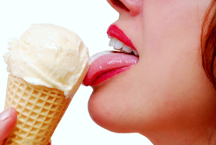 Close-up female lips with red lipstick eating a vanilla ice cream cone