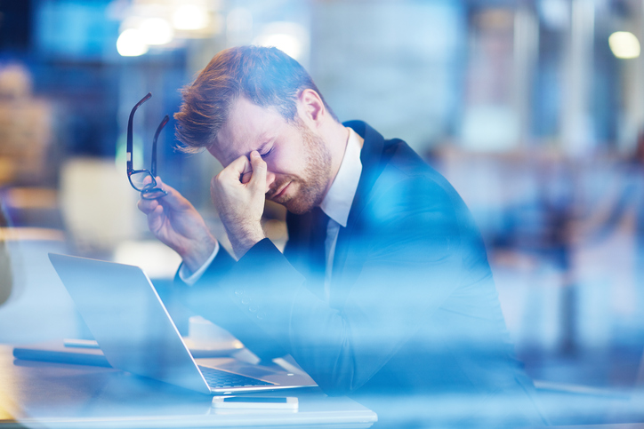 Young tired businessman sitting with his head over laptop