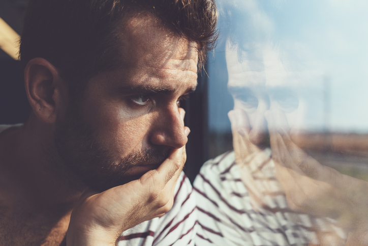 sad man looking through a window