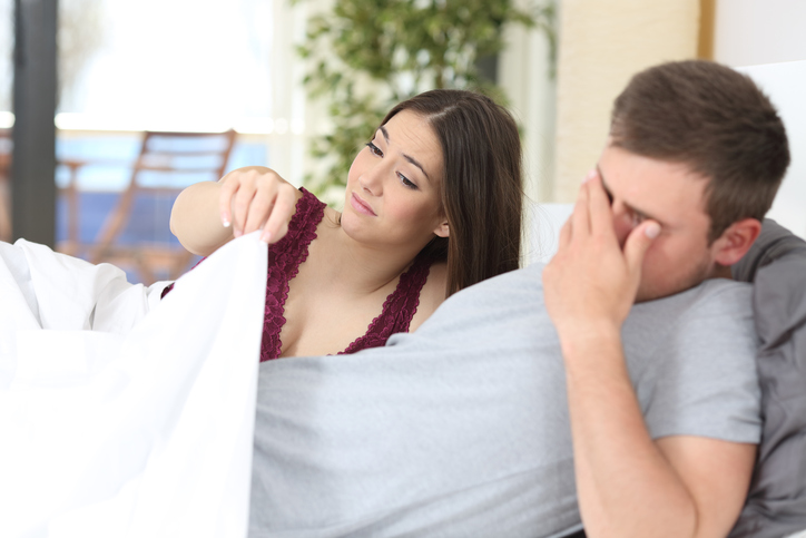 Woman looking at man under covers