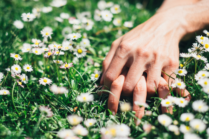 Passion and love on spring concept. Lovers hands on flowers field.