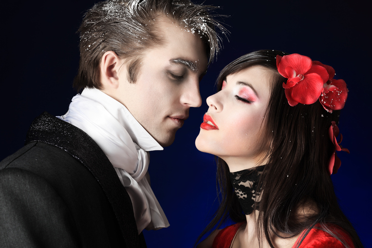 Portrait of a beautiful couple in medieval costumes with vampire style make-up. Shot in a studio.