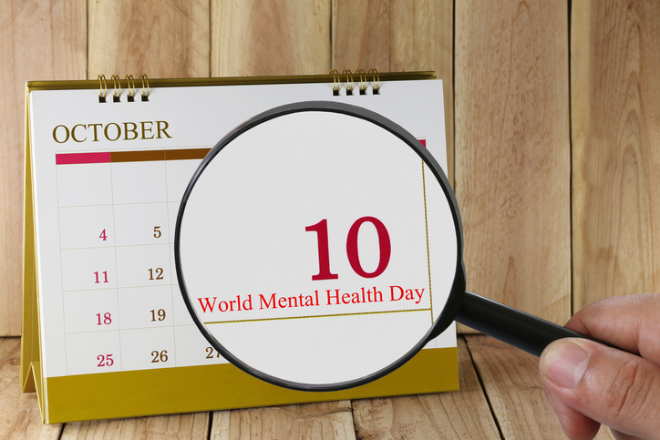 Magnifying glass in hand on calendar you can look World Mental Health Day in 10 October,concept of a public relations campaign Mental health and stress.