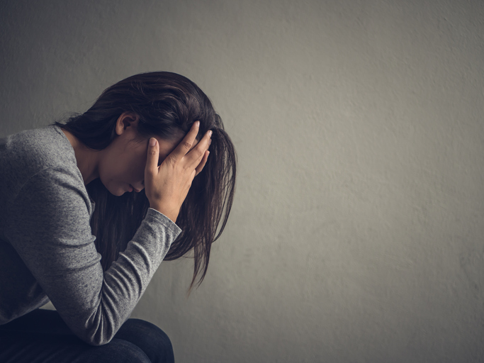 Depressed woman sitting on a chair in dark room at home